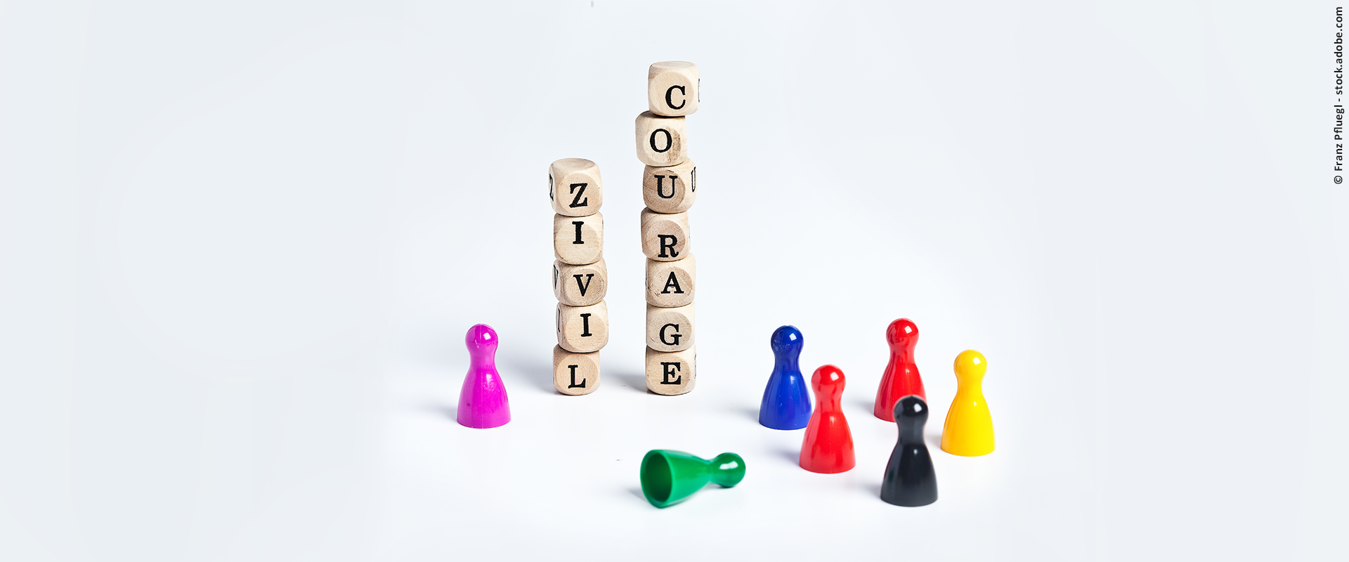 Übereinander gestapelte Buchstabenwürfel mit dem Schriftzug "Zivilcourage", daneben sind bunte Spielfiguren zu sehen