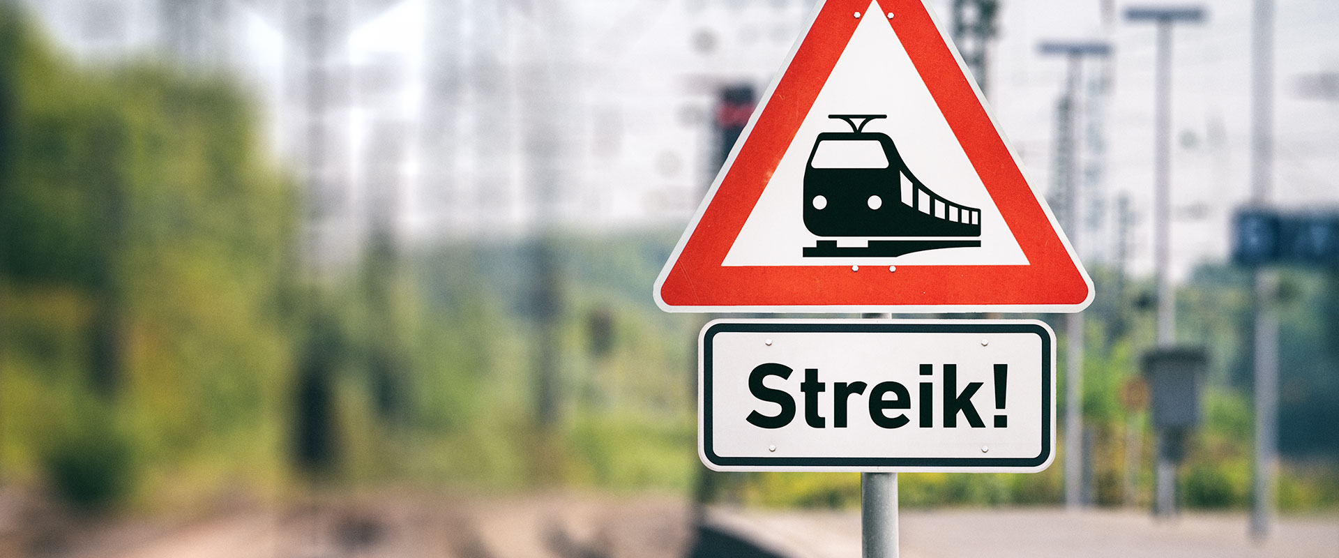 Zwei Schilder, eines mit dem Wort "Streik", eines zeigt einen Zug