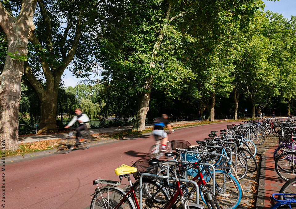 Sitzgelegenheiten am Straßenrand, im Hintergrund Fahrradfahrer