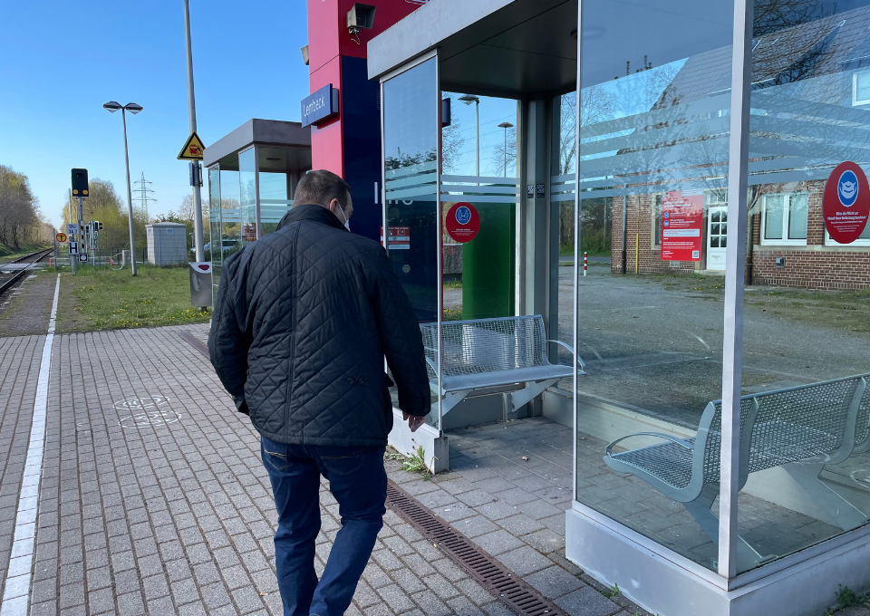 Ein Mann betritt das Wartehäuschen an einem Bahnhof