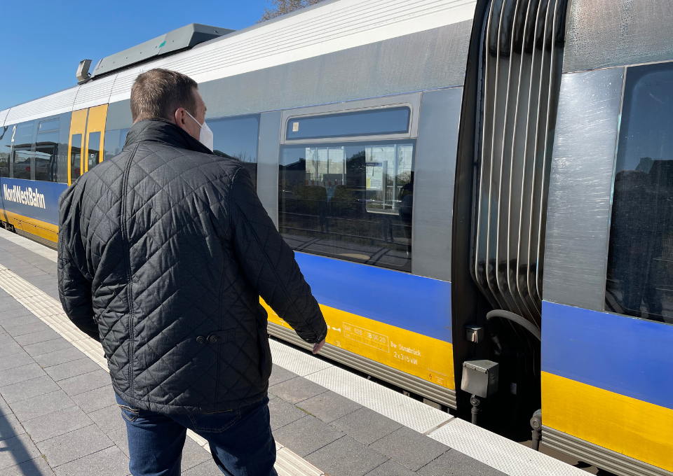 Ein Mann steht am Bahnsteig bei einem einfahrenden Zug