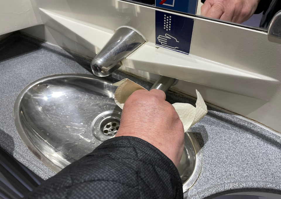 Eine Person überprüft die Funktionalität des Waschbeckens in einer Zugtoilette
