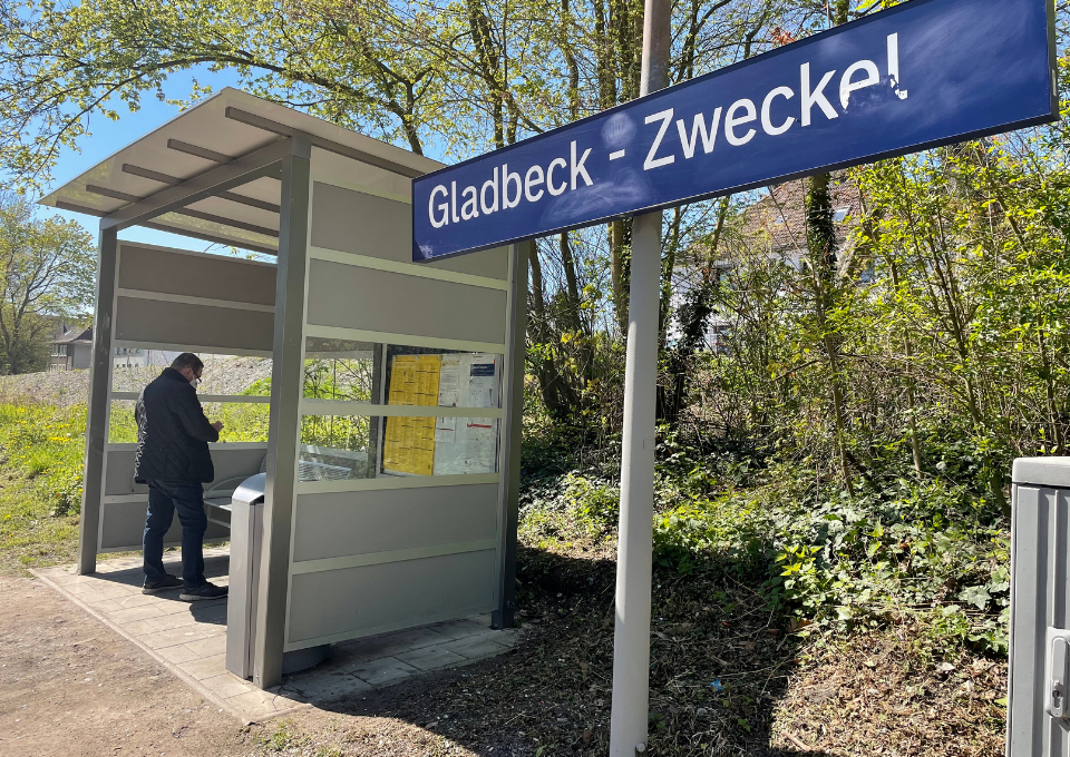 Ein Mann steht im Wartehäuschen am Bahnhof