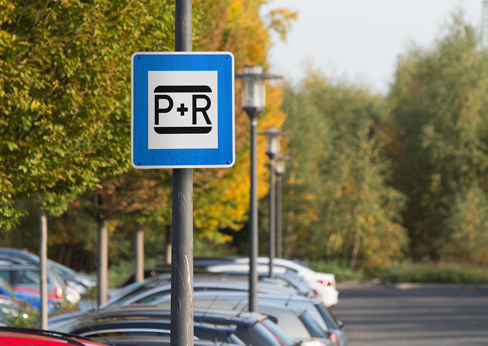 Park+Ride-Schild mit Parkplatz im Hintergrund