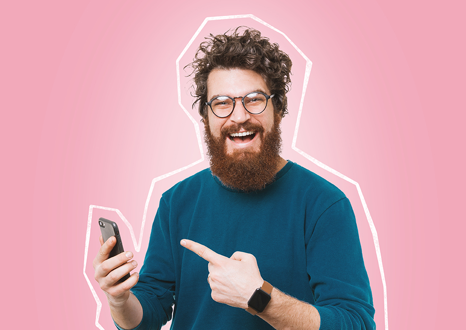 Ein Mann lächelt und zeigt mit dem Zeigefinger auf sein Smartphone