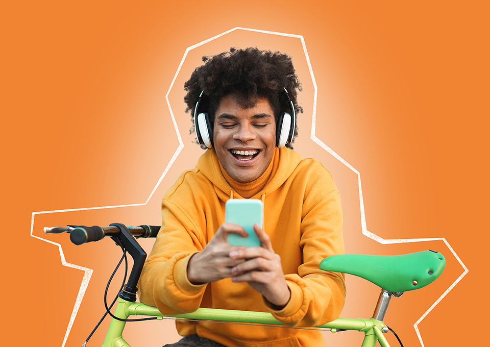 Ein jüngerer Mann stützt sich auf seinem Fahrrad ab, hält sein Smartphone in der Hand und lächelt