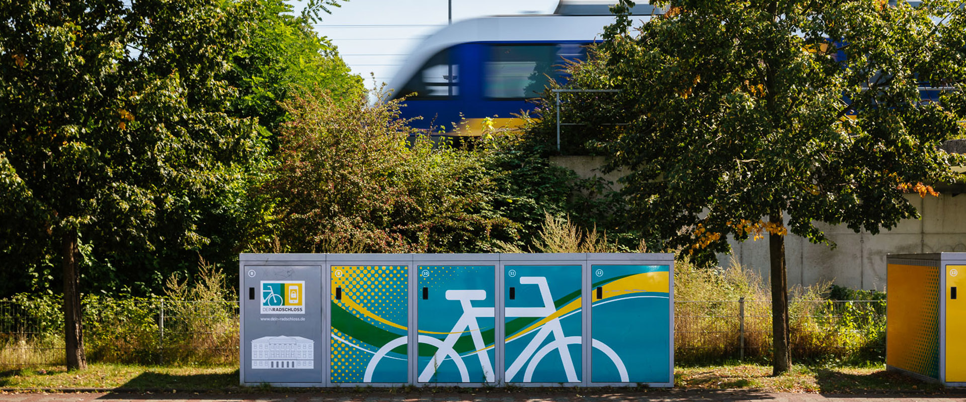 DeinRadschloss-Fahrradboxen, im Hintergrund eine grüne S-Bahn
