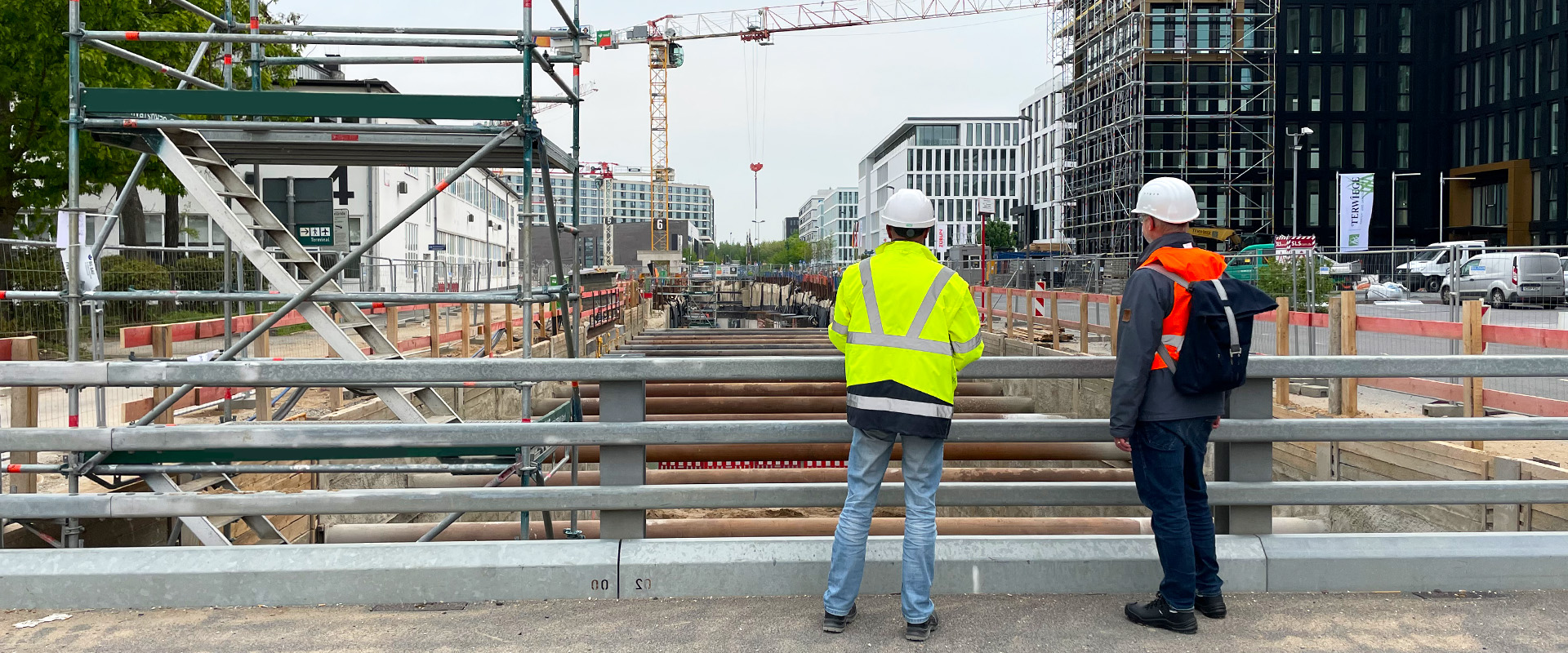 Zwei Menschen stehen auf einer Brücken und schauen in den Baukeller der U81