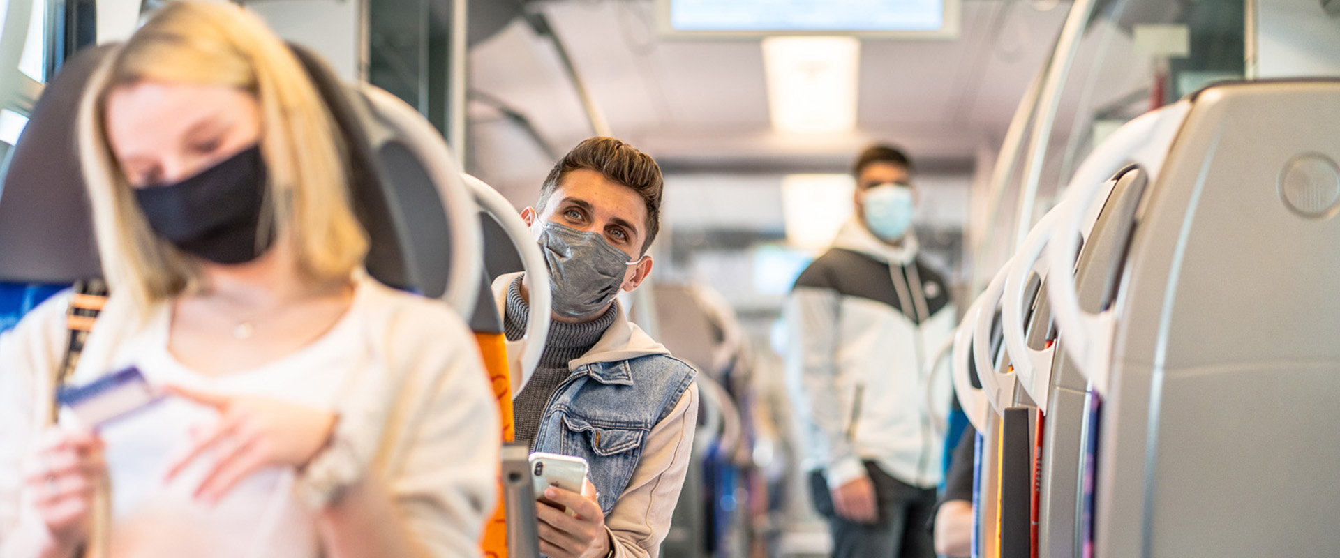 Junge Leute mit Maske sitzen in einem Zug