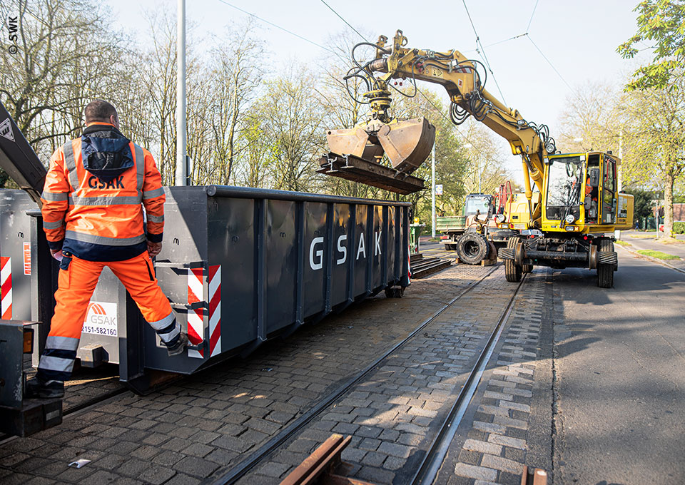 Ein Bagger entsorgt alte Gleise in einem Container