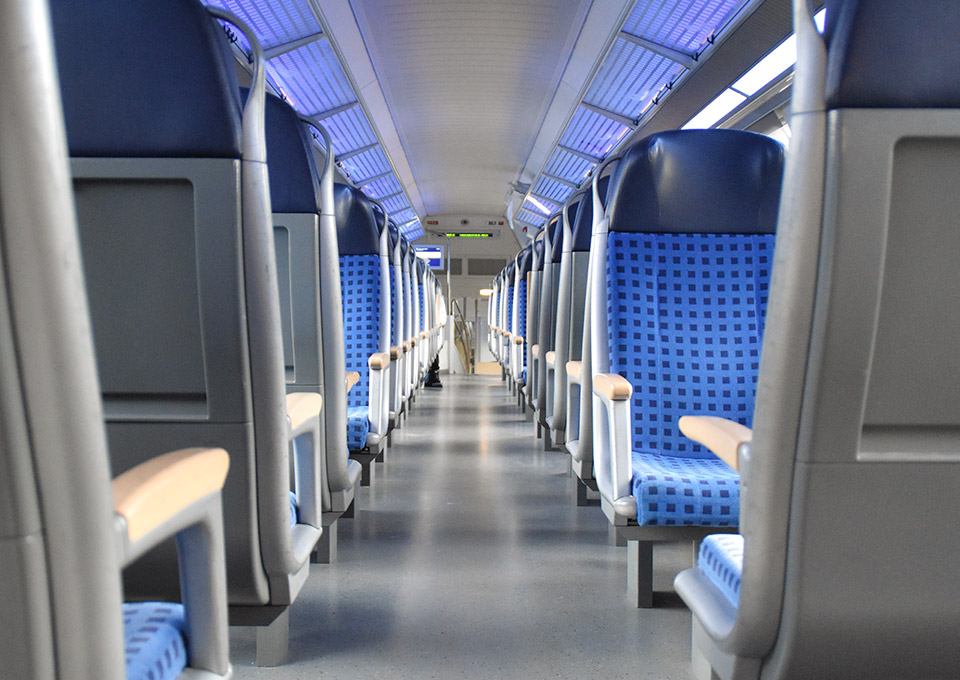 Blick durch den Mittelgang eines Zuges, links und rechts Sitzplätze mit blau gemusterten Polstern