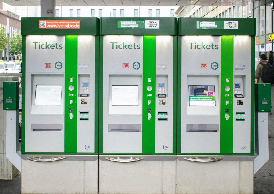 Drei grüne Ticketautomaten nebeneinander mit zwei Entwertern 