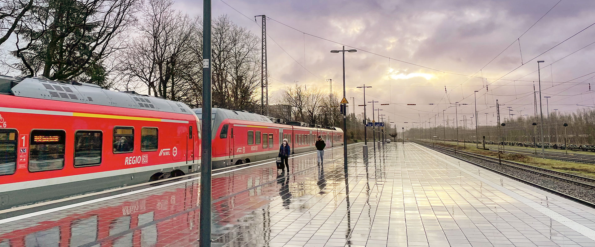 Ein regennasser Bahnsteig, an dem ein roter Regionalzug von DB Regio hält