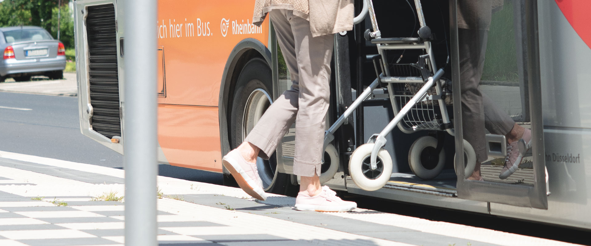 Eine Person mit Rollator steigt an einer Haltestelle in einen Bus