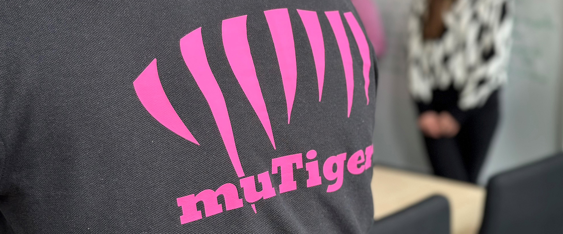 Detailansicht einer Person von hinten, im Bild zu sehen ist ein Shirt mit dem Logo der muTiger-Stiftung