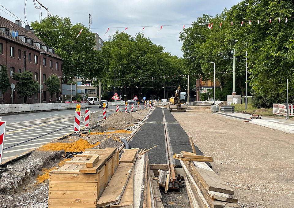 Neubau Haltestelle Brückelstraße: der alte Asphalt ist teilweise abgetragen, im Hintergrund ist eine Baumaschine zu sehen