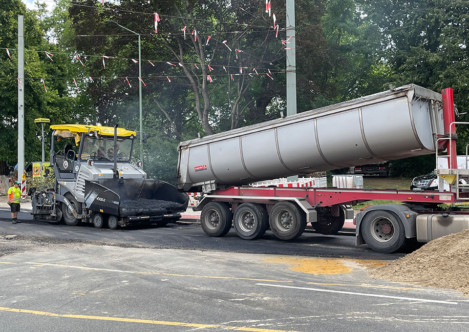 Neubau Haltestelle Brückelstraße: Asphaltierarbeiten, eine Baumaschine und ein Kipplaster sind zu sehen