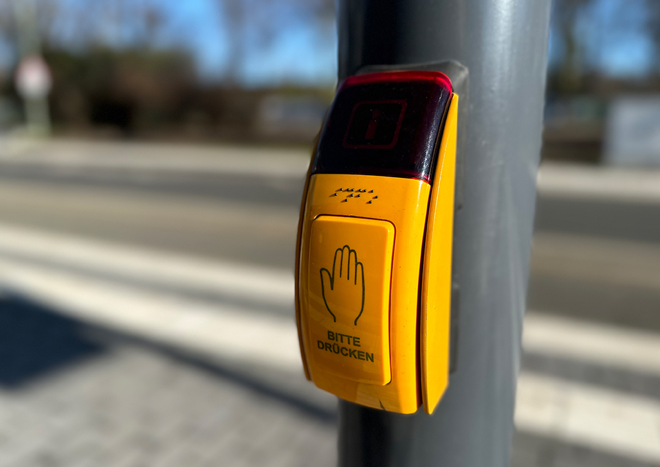 Neubau Haltestelle Brückelstraße: Detailaufnahme eines Anforderungstasters einer Ampel mit dem Schriftzug "Bitte drücken" und Blindenschrift