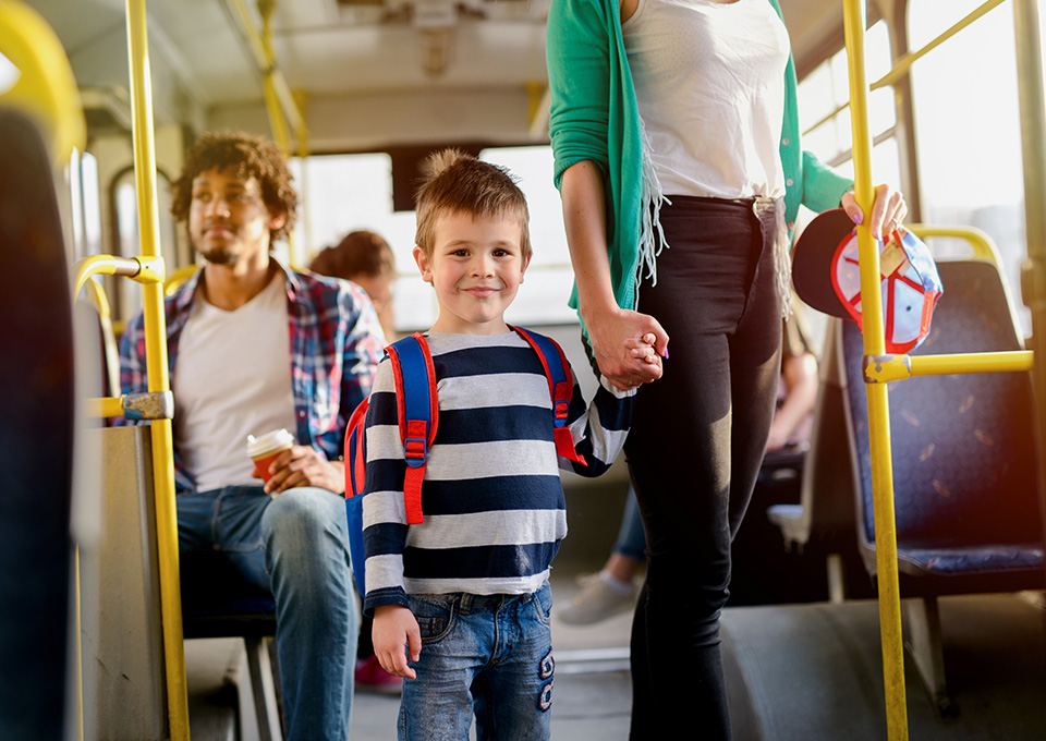 Mehrere Personen in einem Bus, im Vordergrund ist ein kleiner Junge zu sehen, an der Hand eines Erwachsenen