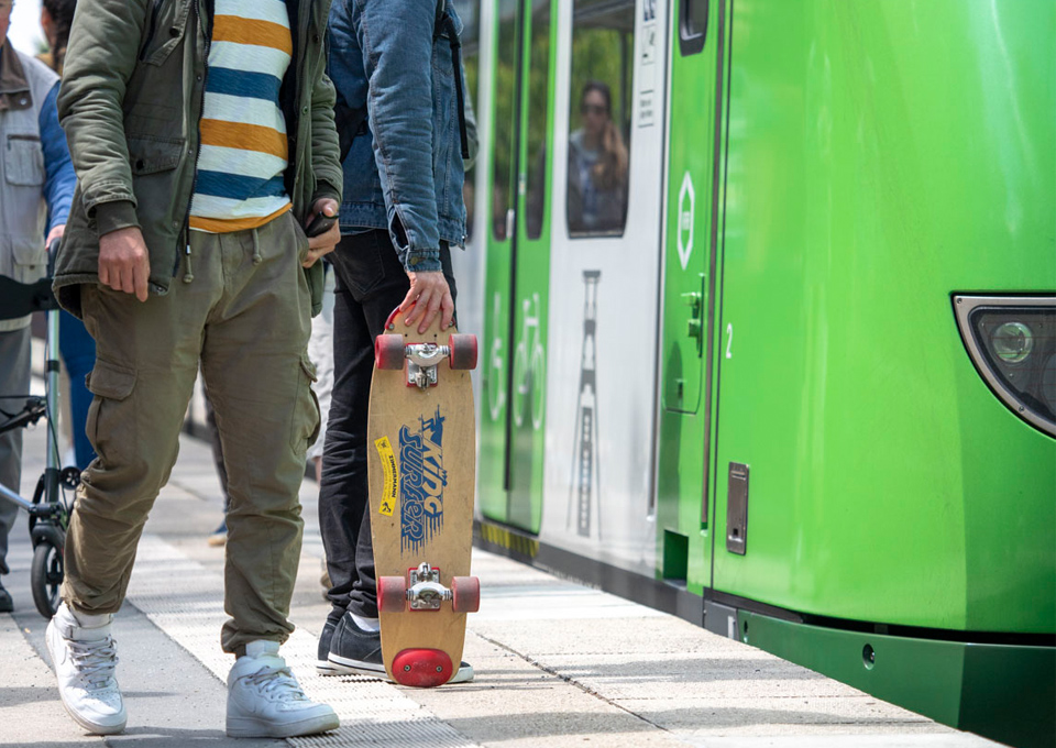 Ein Mann mit Skateboard läuft am Bahnsteig neben einem Zug