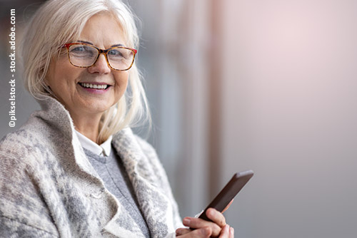 Eine ältere Dame hält glücklich ein Handy in der Hand